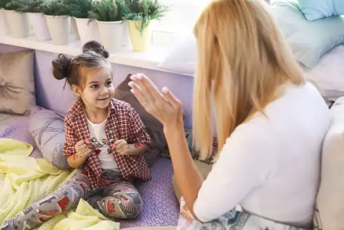 Young girl is playing with mother near the window, signifying parent child therapy