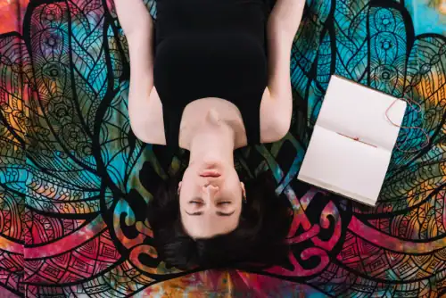 overhead-view-eyes-closed-woman-lying-near-open-blank-book-blanket signifying rapid transformational therpay and hypnosis